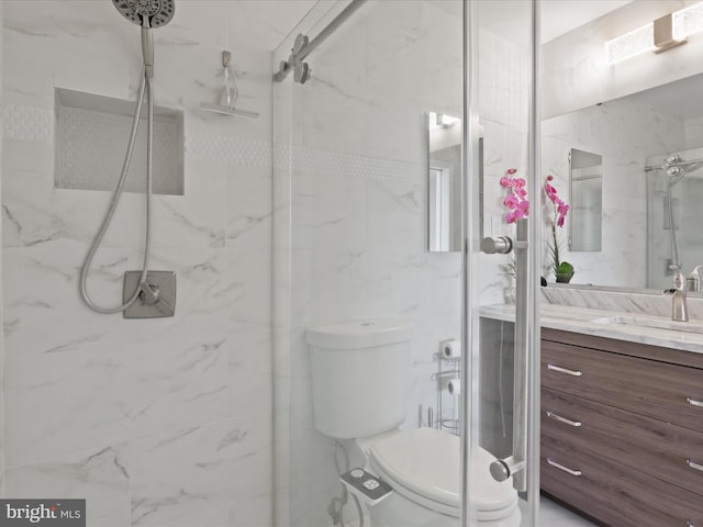 bathroom with vanity, a shower with door, tile walls, and toilet