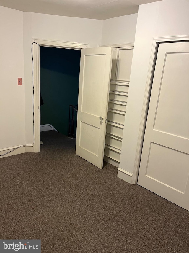 unfurnished bedroom with a closet and dark colored carpet