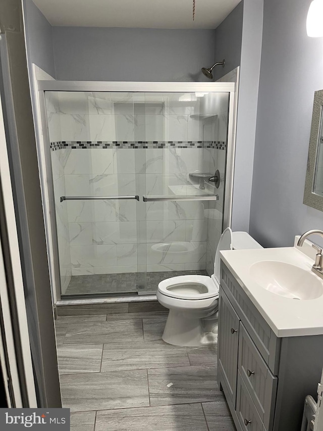 bathroom featuring vanity, toilet, and an enclosed shower