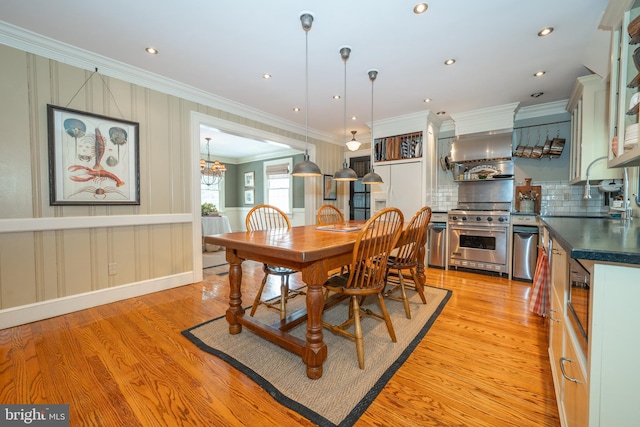 dining room with sink, ornamental molding, and light hardwood / wood-style floors