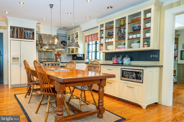 kitchen featuring decorative light fixtures, backsplash, crown molding, white built in fridge, and light wood-type flooring