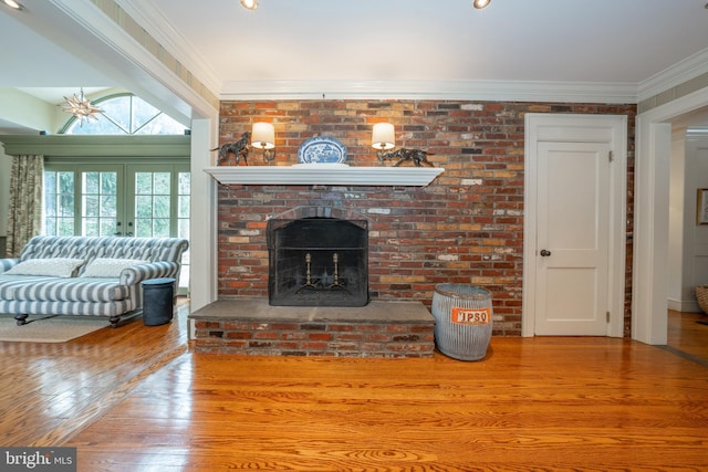 unfurnished living room with a brick fireplace, wood-type flooring, crown molding, and french doors