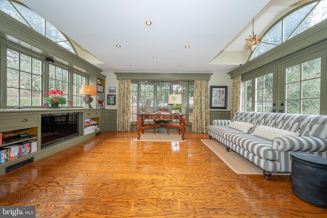 living room featuring ceiling fan, a high ceiling, a wealth of natural light, and light hardwood / wood-style flooring