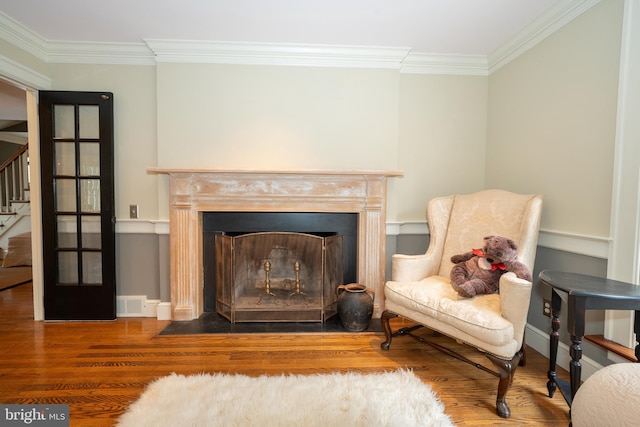 living area with wood-type flooring and crown molding