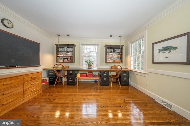 office area with plenty of natural light, dark hardwood / wood-style floors, crown molding, and built in desk