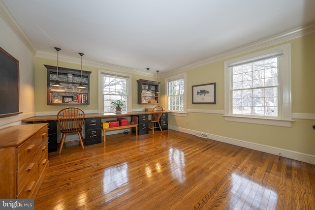 office with crown molding, plenty of natural light, built in desk, and wood-type flooring