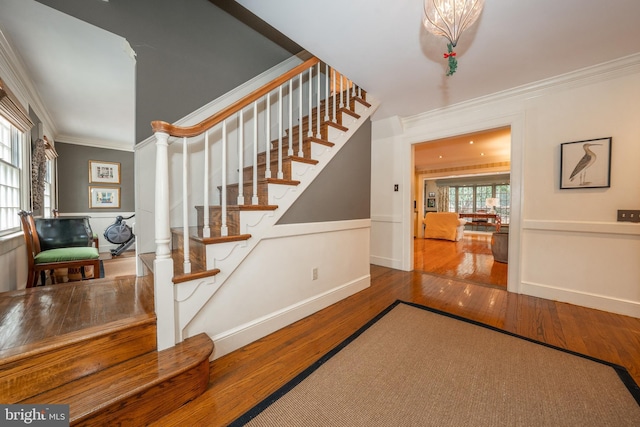 staircase with wood-type flooring and ornamental molding