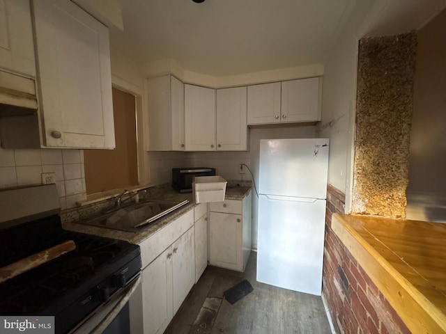 kitchen with backsplash, appliances with stainless steel finishes, sink, and white cabinetry