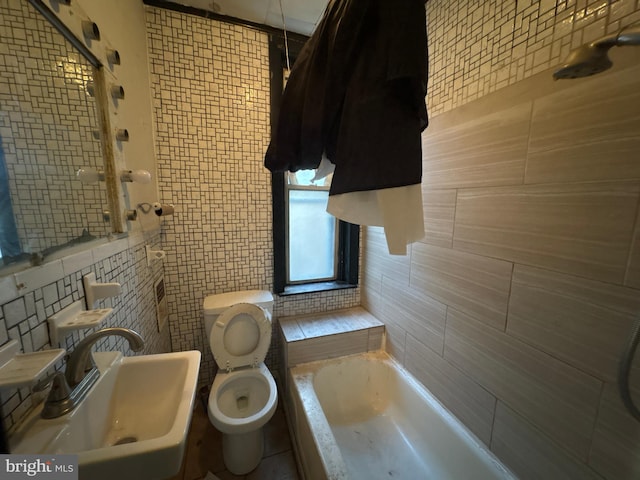 bathroom featuring toilet, a bathtub, tile walls, and sink