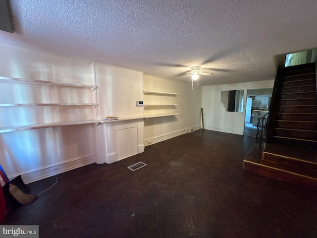 unfurnished living room with ceiling fan and a textured ceiling