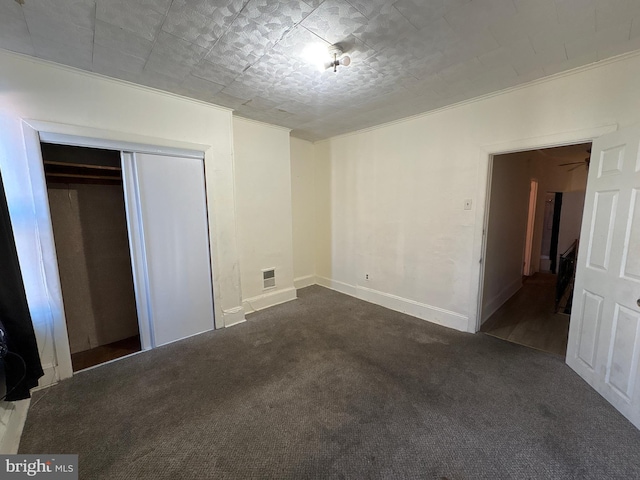 unfurnished bedroom with a closet and dark colored carpet