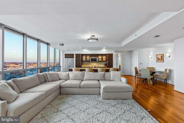 living room with floor to ceiling windows, sink, and hardwood / wood-style flooring