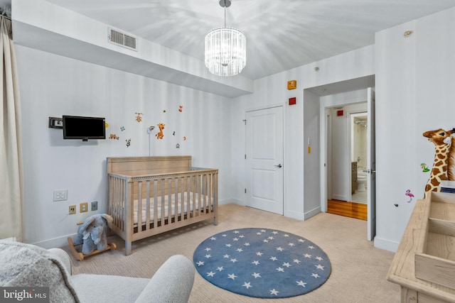 bedroom with light carpet, a chandelier, and a nursery area