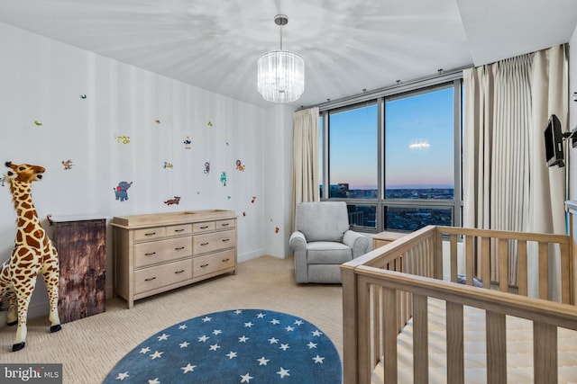 bedroom featuring light carpet, a wall of windows, a crib, and a chandelier