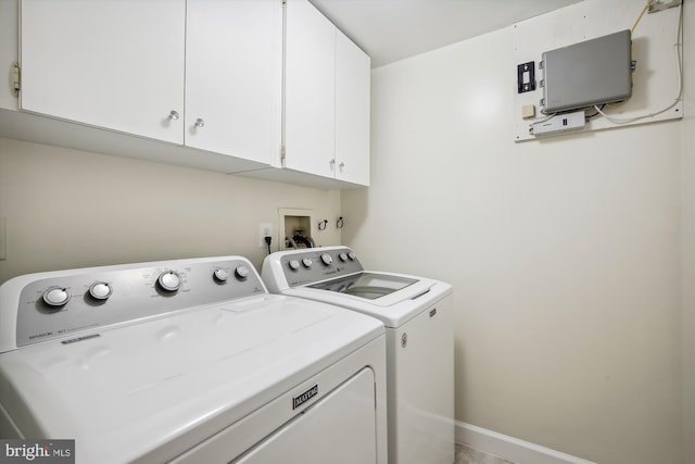 clothes washing area featuring independent washer and dryer and cabinets