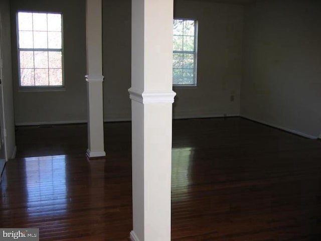 empty room with dark hardwood / wood-style floors and ornate columns