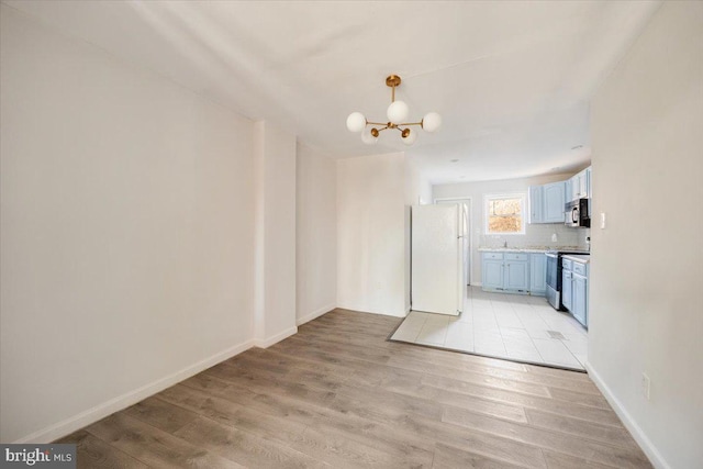 unfurnished dining area featuring an inviting chandelier and light hardwood / wood-style flooring