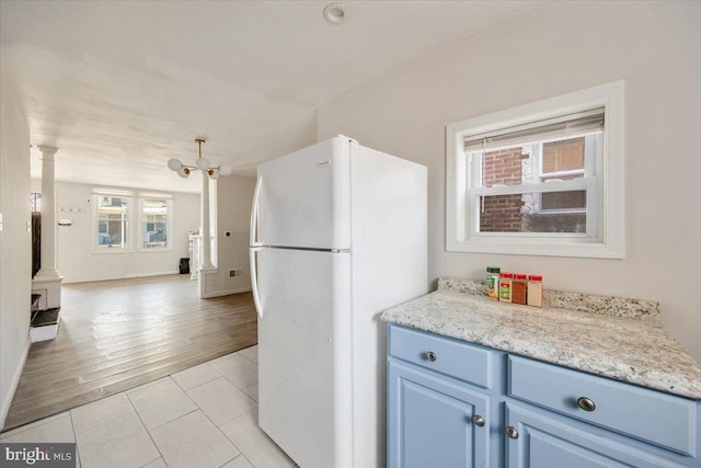 kitchen featuring white fridge, an inviting chandelier, light hardwood / wood-style flooring, light stone countertops, and decorative columns