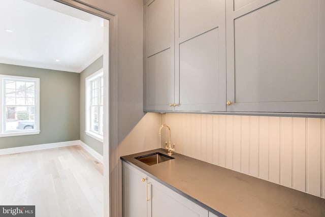 kitchen featuring crown molding, light hardwood / wood-style floors, plenty of natural light, and sink