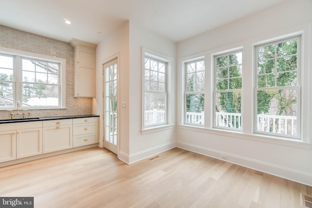 kitchen with light hardwood / wood-style floors, tasteful backsplash, and sink