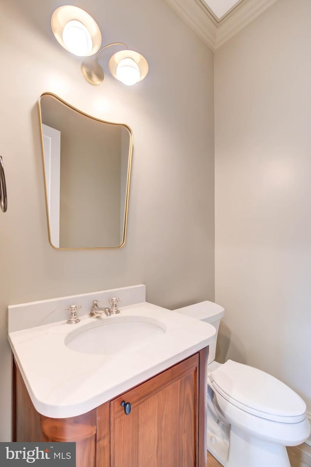 bathroom featuring toilet, vanity, and crown molding