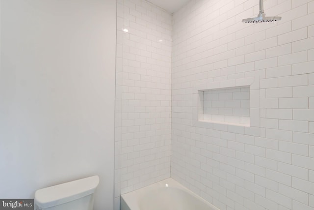 bathroom featuring toilet and tiled shower / bath