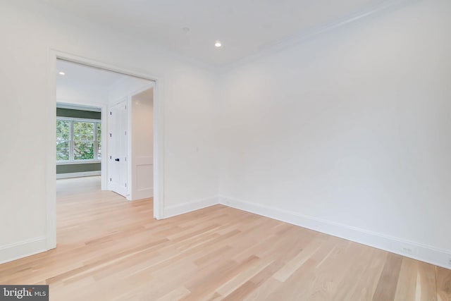 spare room featuring light wood-type flooring and crown molding