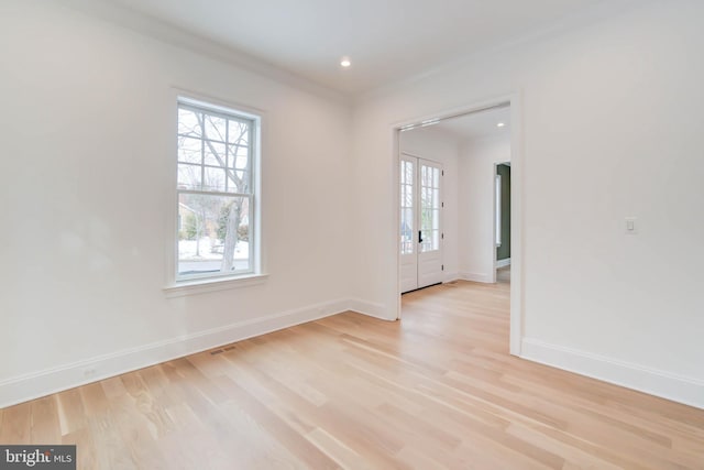 empty room featuring light wood-type flooring and ornamental molding