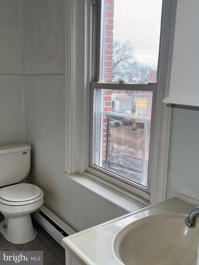 bathroom with hardwood / wood-style flooring, sink, toilet, and a baseboard heating unit