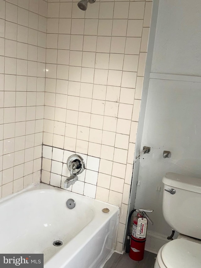 bathroom with toilet and tiled shower / bath