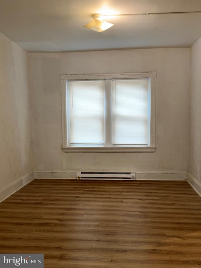 empty room with dark wood-type flooring and baseboard heating