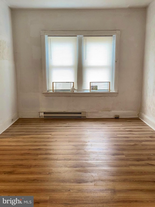 empty room with baseboard heating and wood-type flooring