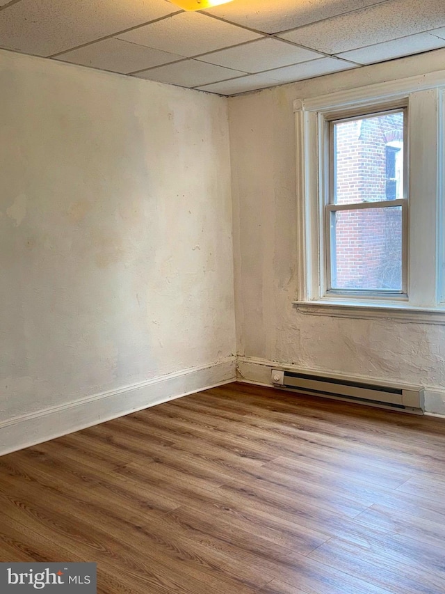 spare room with a paneled ceiling, wood-type flooring, and a baseboard radiator