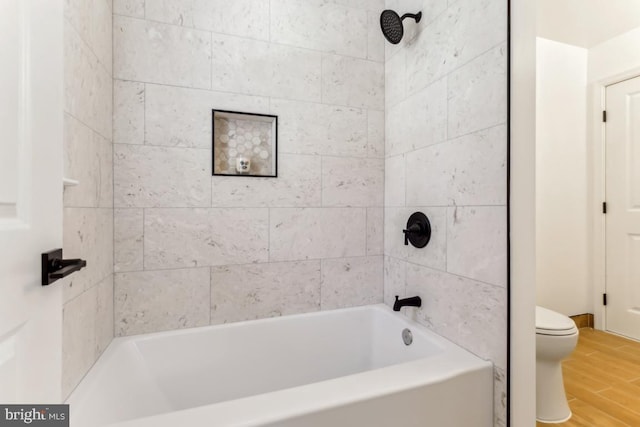 bathroom with toilet, tiled shower / bath combo, and hardwood / wood-style floors