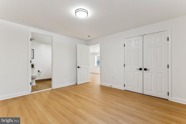 unfurnished bedroom with a closet, connected bathroom, and light hardwood / wood-style flooring