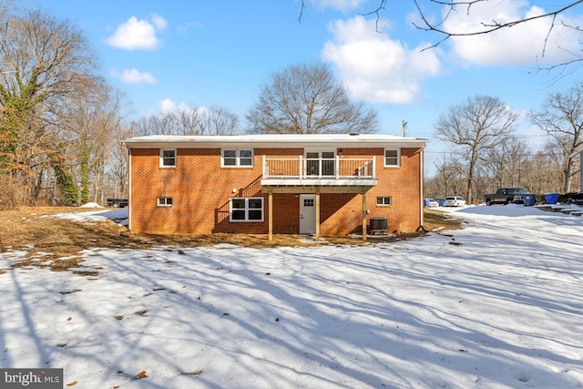 snow covered back of property with central AC and a deck