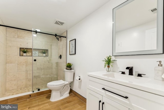 bathroom with toilet, vanity, and a tile shower