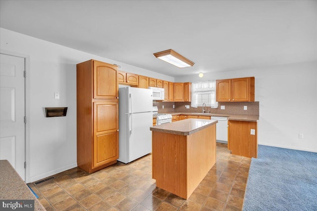 kitchen featuring sink, white appliances, tasteful backsplash, and a kitchen island