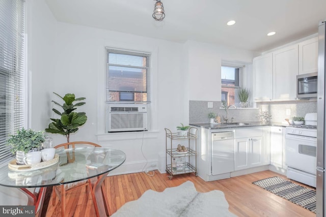 kitchen featuring tasteful backsplash, sink, white cabinets, light hardwood / wood-style floors, and white appliances