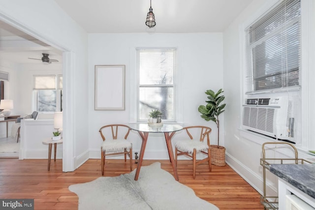 living area featuring ceiling fan, cooling unit, and light hardwood / wood-style floors