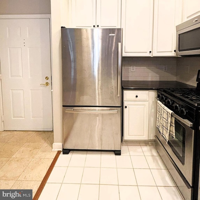 kitchen featuring white cabinetry, appliances with stainless steel finishes, light tile patterned flooring, and backsplash