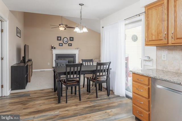 dining space featuring lofted ceiling, ceiling fan with notable chandelier, and dark hardwood / wood-style floors