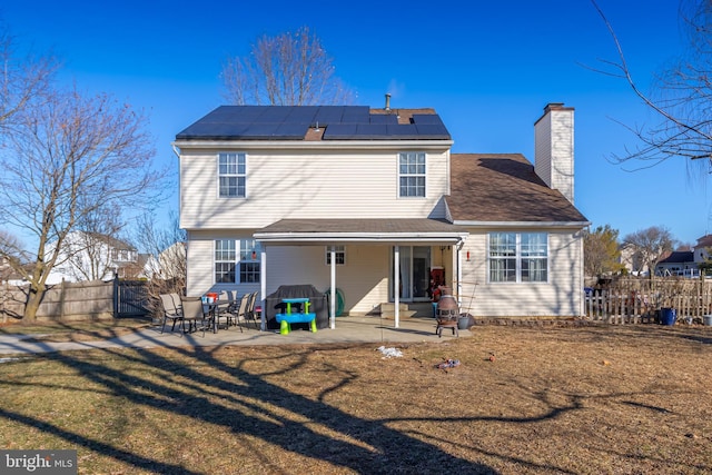 back of house with a yard, solar panels, and a patio