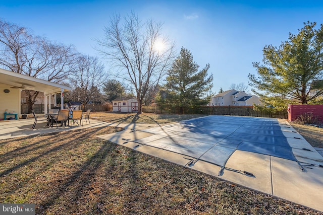 view of pool with a storage shed and a patio