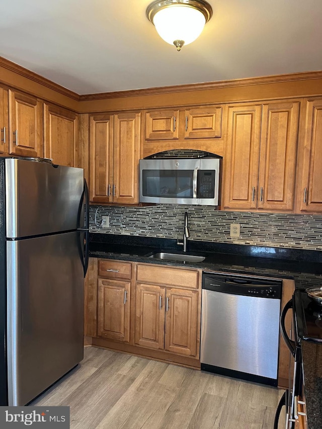 kitchen featuring dark stone countertops, sink, stainless steel appliances, and light hardwood / wood-style floors