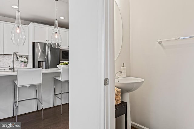 bathroom with hardwood / wood-style flooring, sink, and backsplash