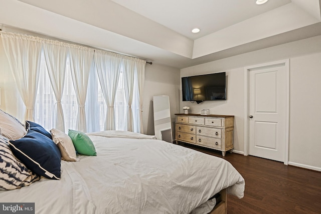 bedroom with dark hardwood / wood-style floors and a raised ceiling