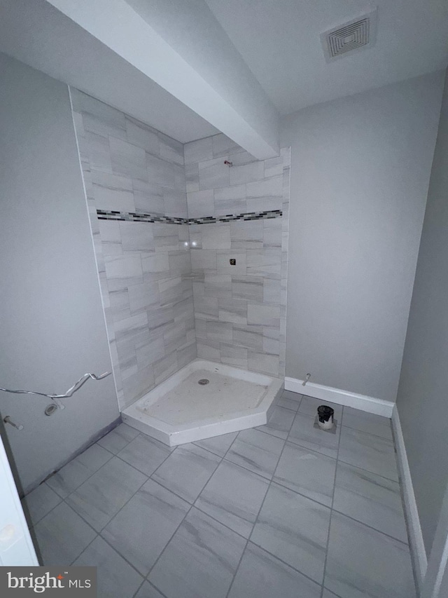 bathroom with tile patterned floors, beam ceiling, and tiled shower