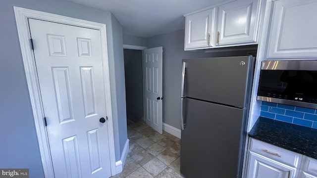 kitchen featuring dark stone countertops, stainless steel appliances, and white cabinetry