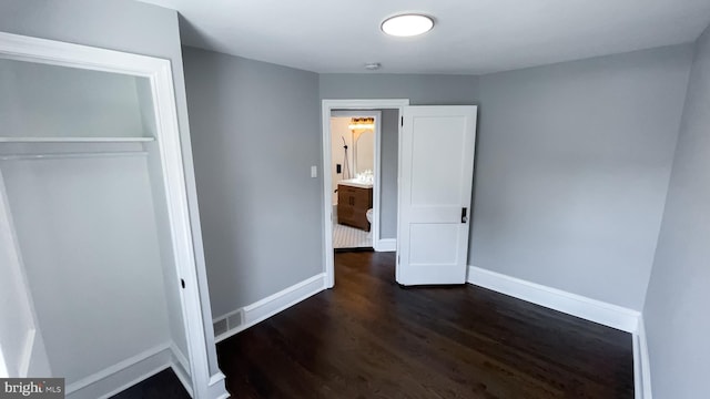 unfurnished bedroom with a closet and dark hardwood / wood-style floors